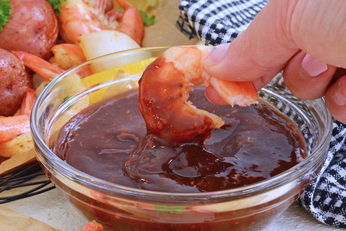 dipping shrimp into balsamic cocktail sauce