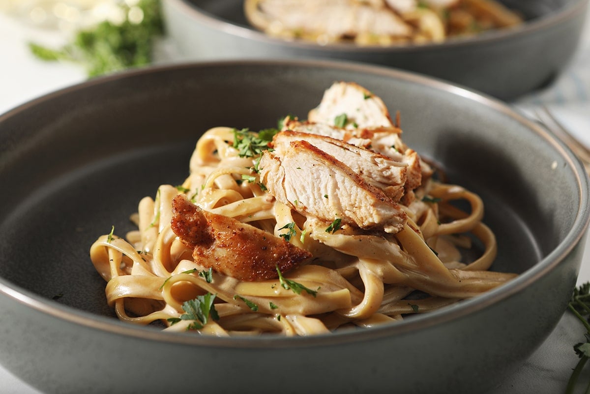 side view of sliced chicken on pasta