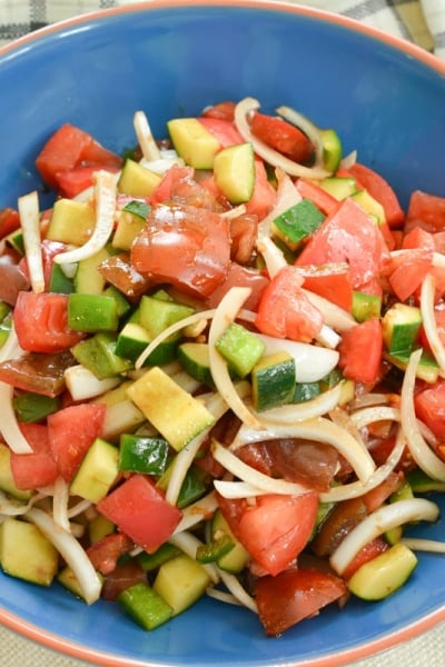 overhead of cucumber tomato salad recipe in a blue bowl