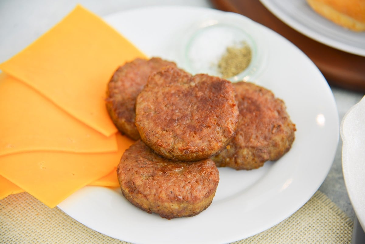 browned sausage patties with cheddar cheese on a white plate 