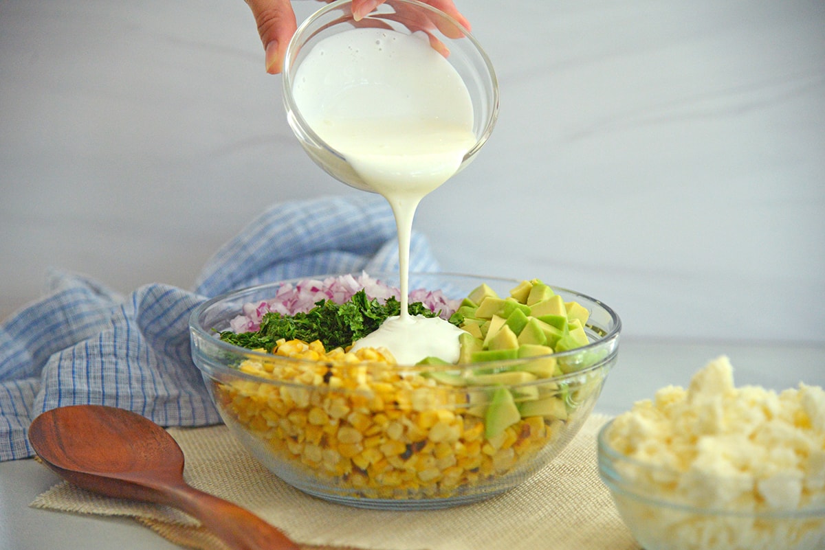 pouring creamy lime dressing over fresh ingredients 
