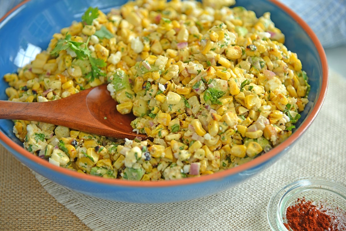 wooden spoon digging into a corn salad 