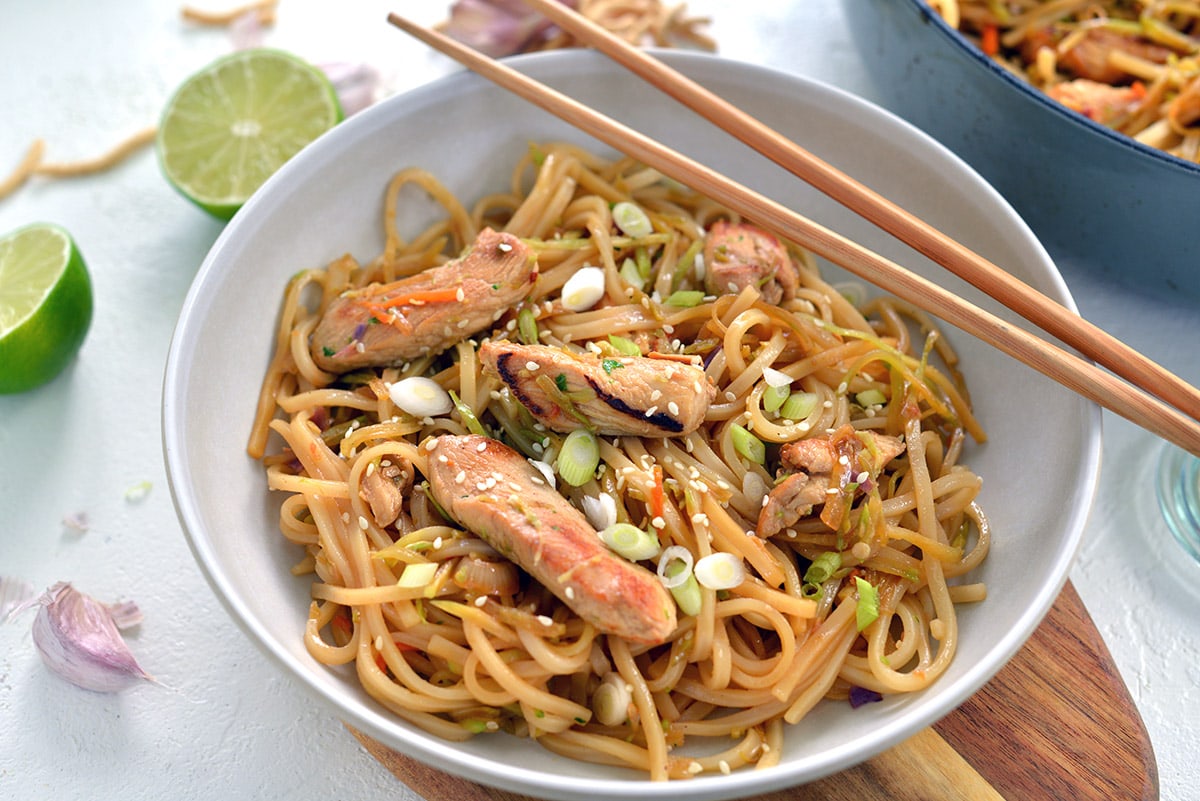 rice noodle stir fry in a white bowl with chopsticks 