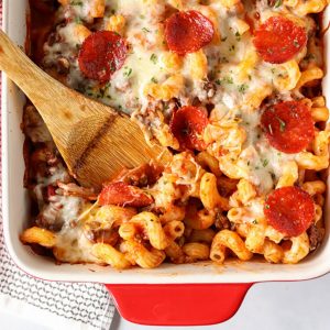 wooden spoon in baked pasta with pepperoni