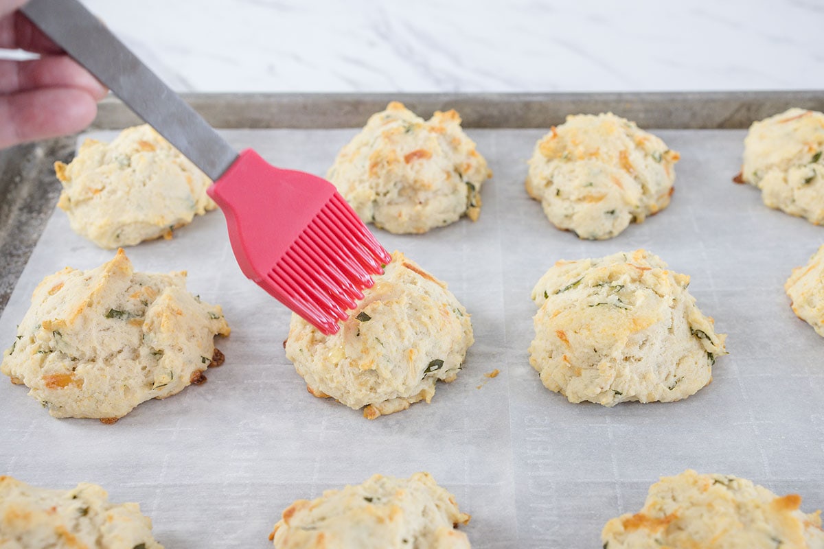 basting drop biscuits on a baking sheet 