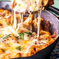 spoon scooping out cheese tortellini from a skillet