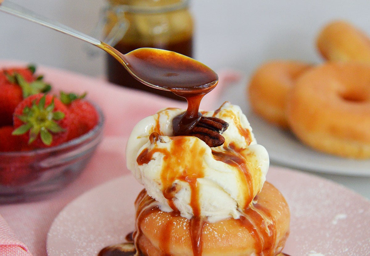 spooning bourbon caramel sauce over sundae 