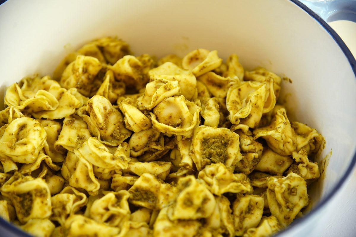 cooked tortellini in pesto sauce in a cooking vessel 