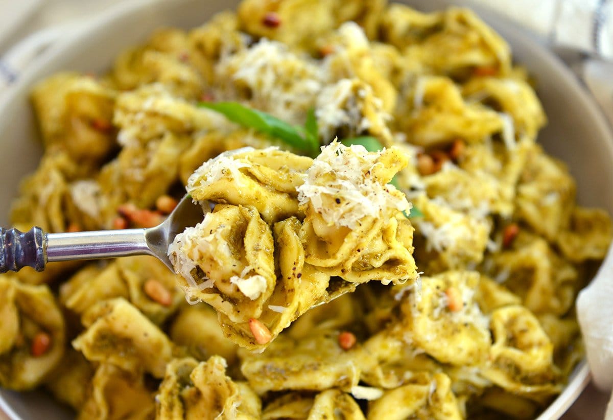 spoon holding 3 pieces of tortellini in sauce with cheese