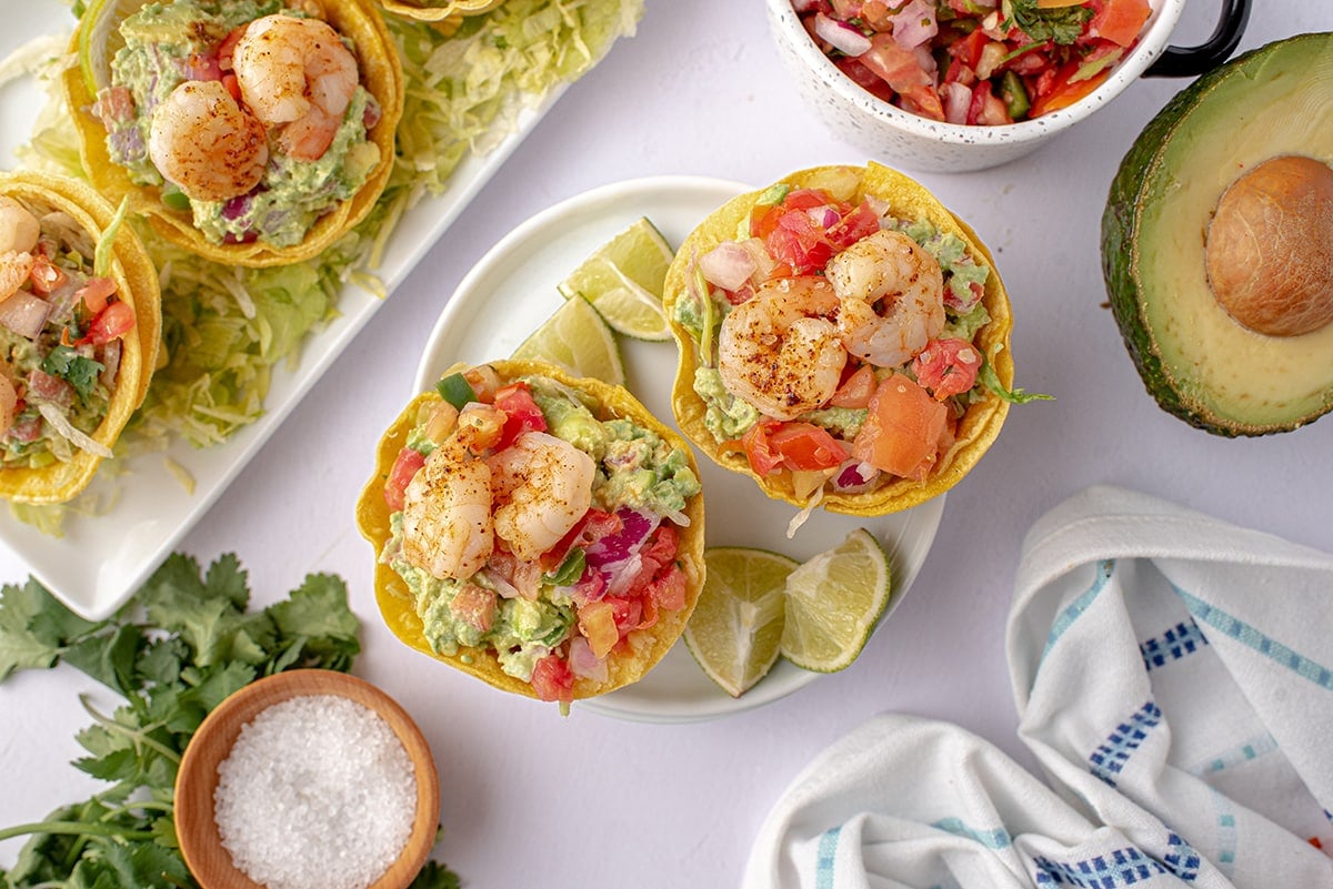 overhead of shrimp tostadas 
on a white plate with lime wedges 