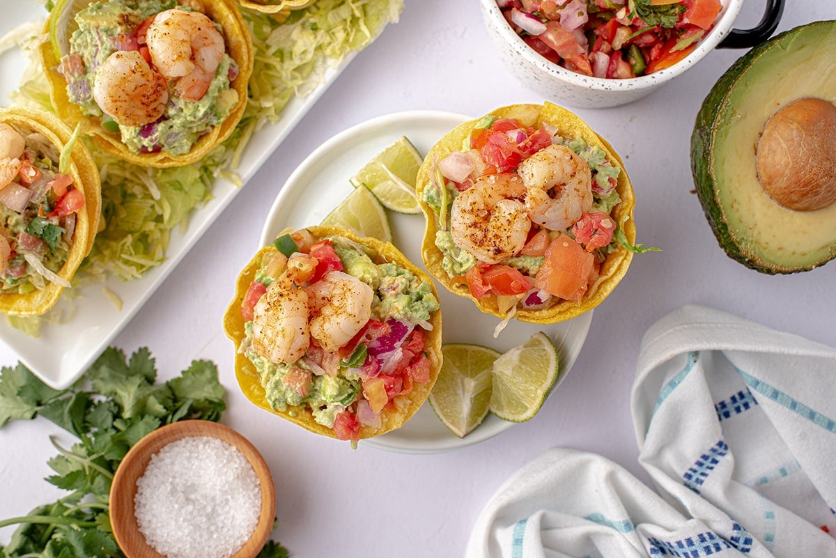 overhead of tostada cups on a white plate with lime wedges 