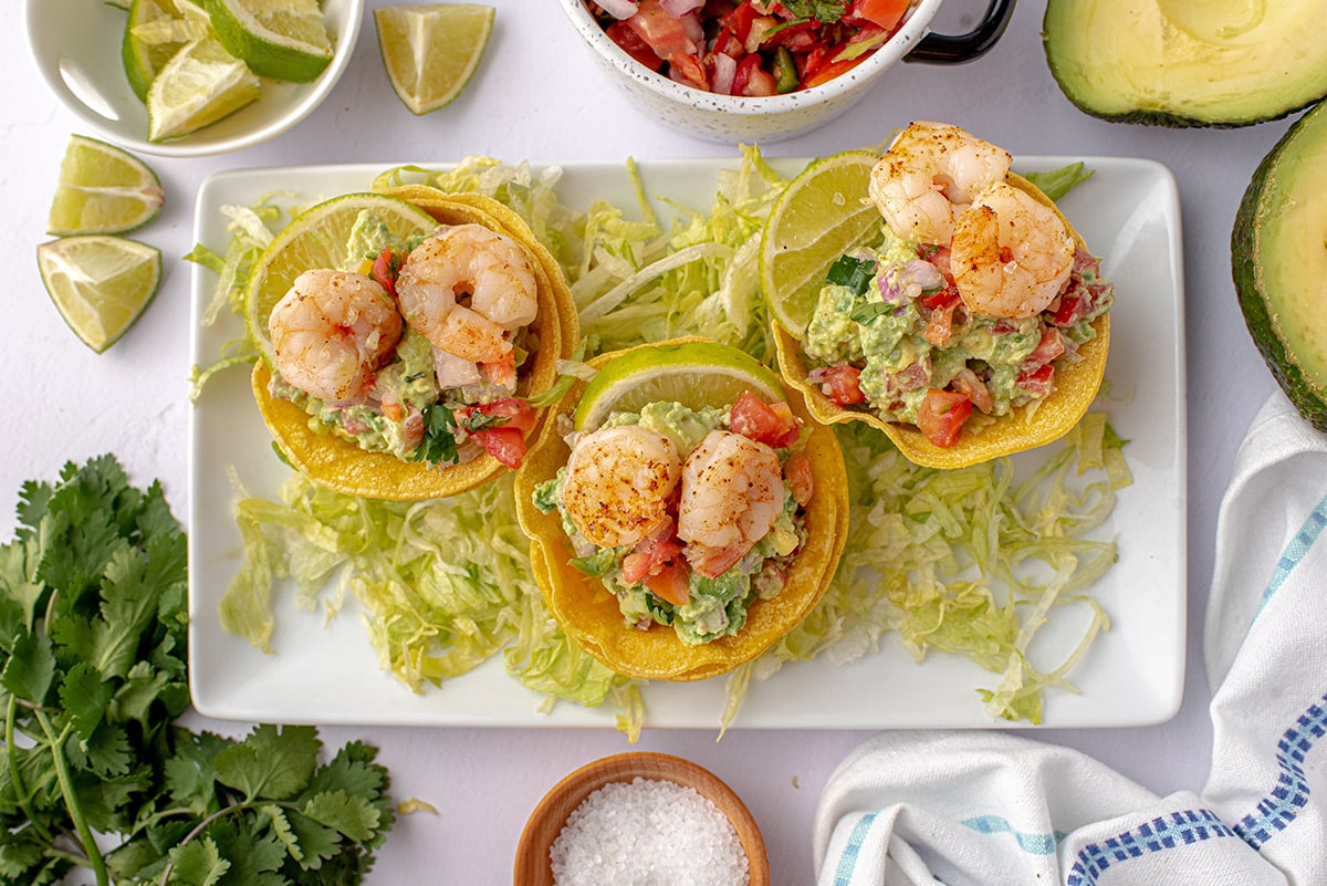 overhead of shrimp tostada cups on a serving platter with shredded lettuce