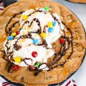 close up of skillet cookie with ice cream, sauce and m&ms