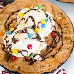 close up of skillet cookie with ice cream, sauce and m&ms