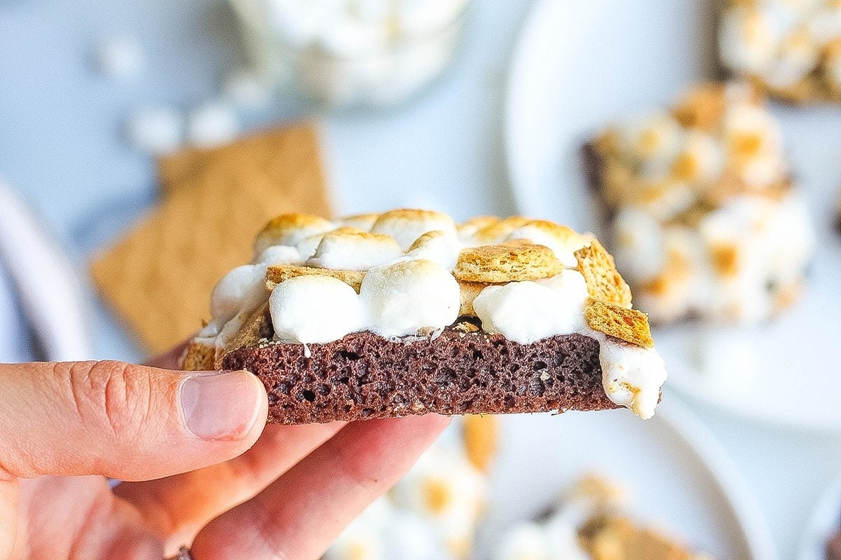 hand holding a brownie topped with graham crackers and marshmallows 