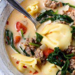 bowl of tortellini soup with spoon in it