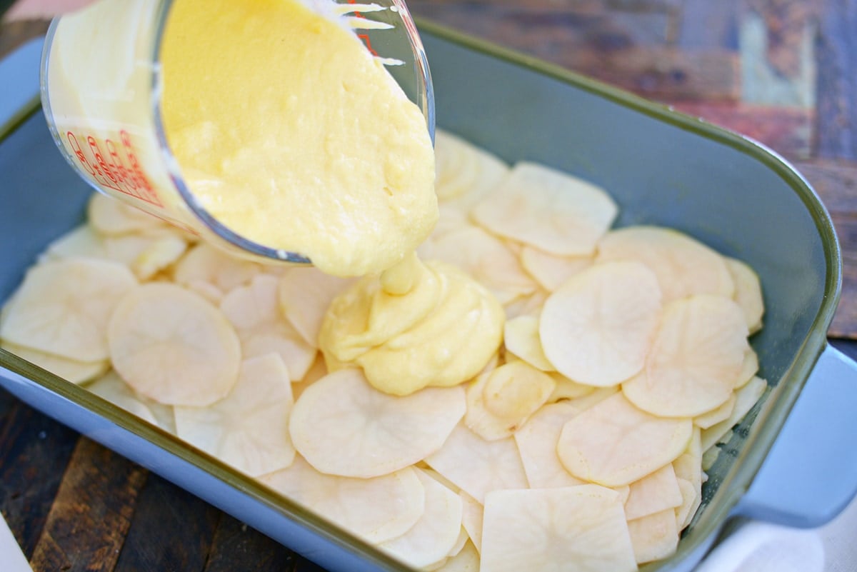 pouring roux over sliced potatoes 