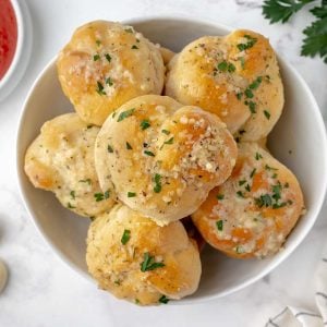 bowl of buttery garlic knots with marinara sauce