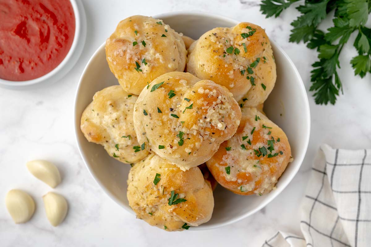 bowl of buttery garlic knots with marinara sauce