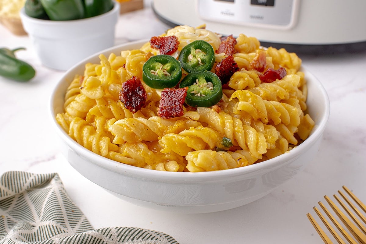 angle view of mac and cheese in a bowl with jalapeno slices 