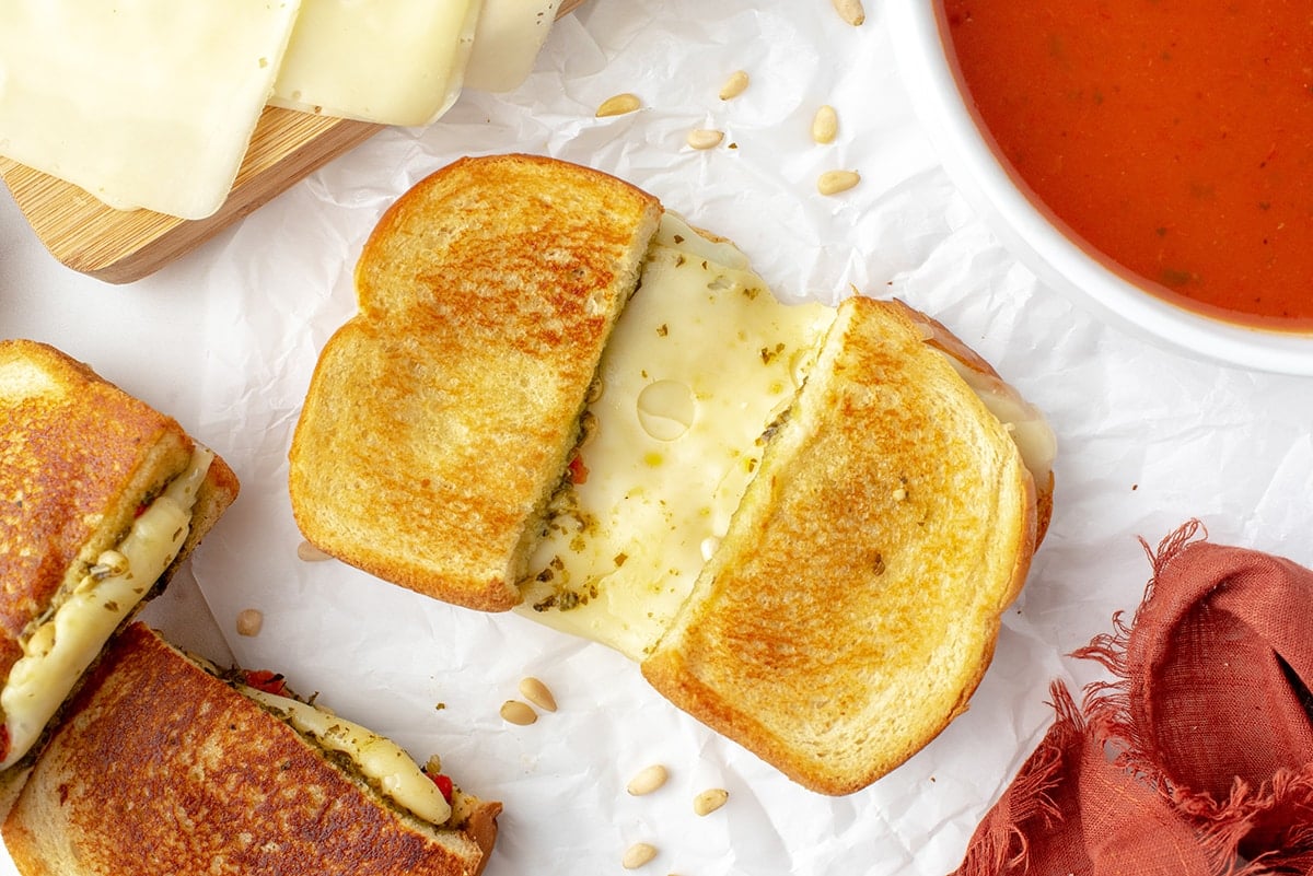 cheese pulling in a grilled sandwich with soup 
