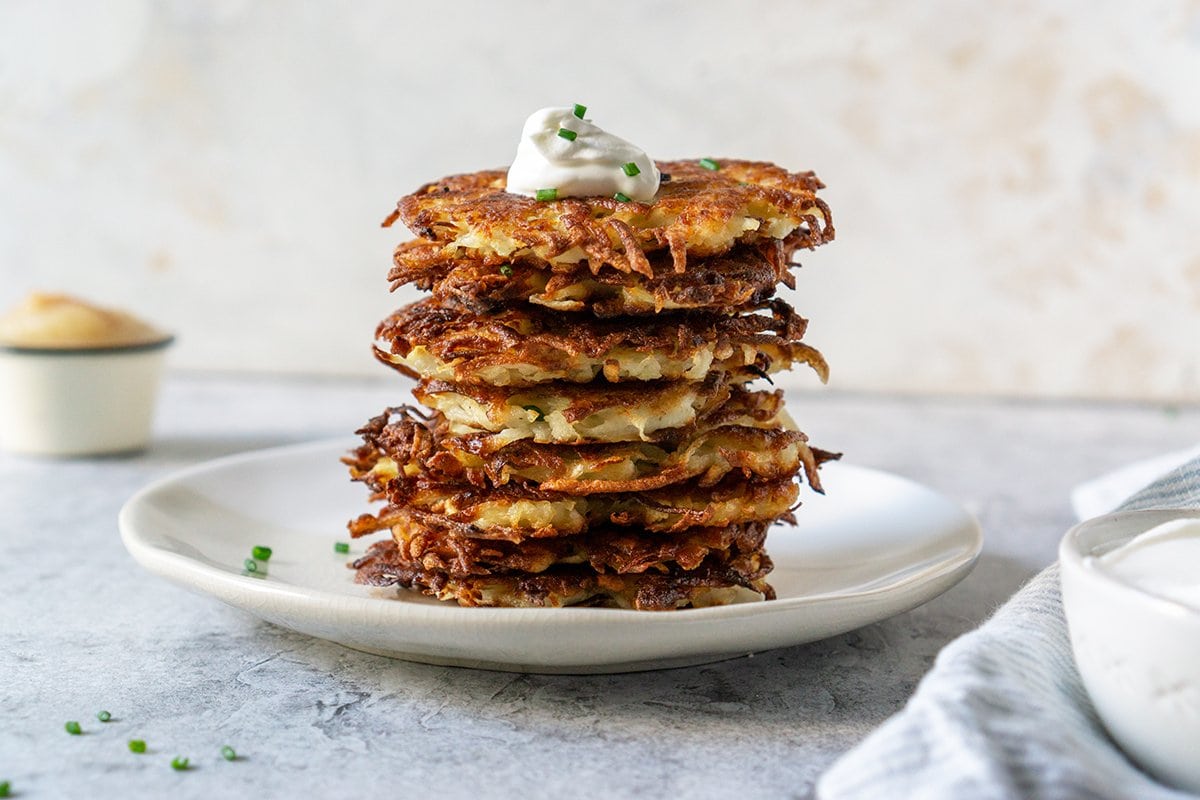 head-on of a stack of latkes with sour cream 