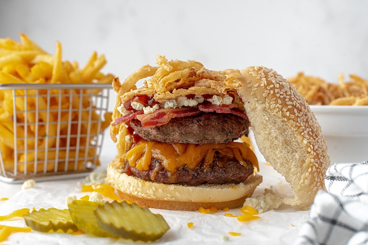 assembled cowboy burger with fried in the background 