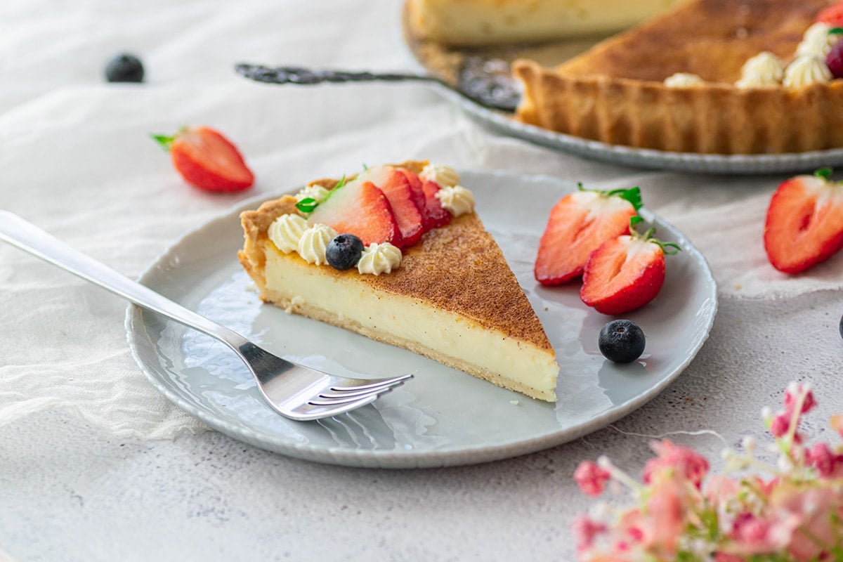 slice of custard pie on a plate with fresh fruit