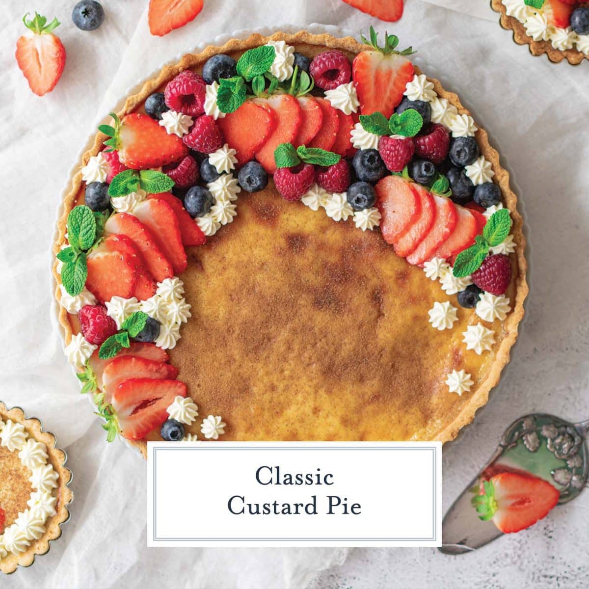 overhead of custard pie decorated with fresh berries and whipped cream