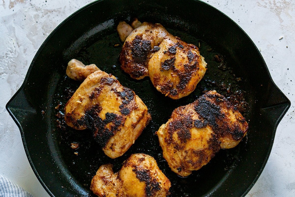 chicken thighs cooking in a skillet