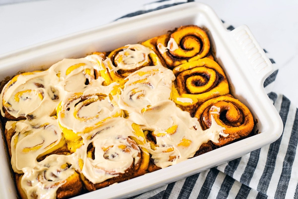 icing slathered on pumpkin cinnamon rolls