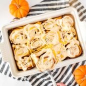 pumpkin cinnamon rolls with frosting in a baking dish