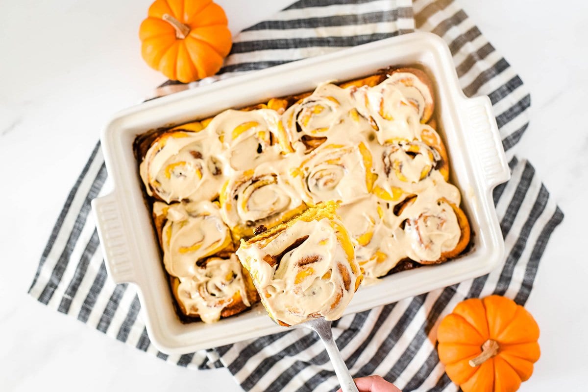 pumpkin cinnamon rolls with frosting in a baking dish