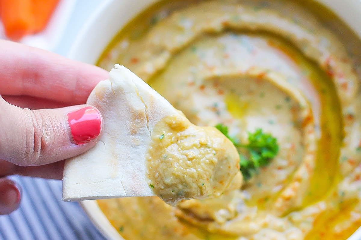 hand holding pita bread with baba ganoush 