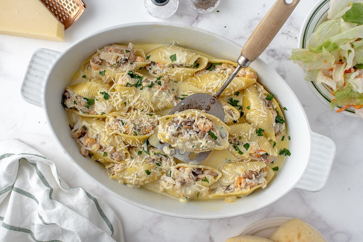 spatula serving a seafood stuffed pasta shell 