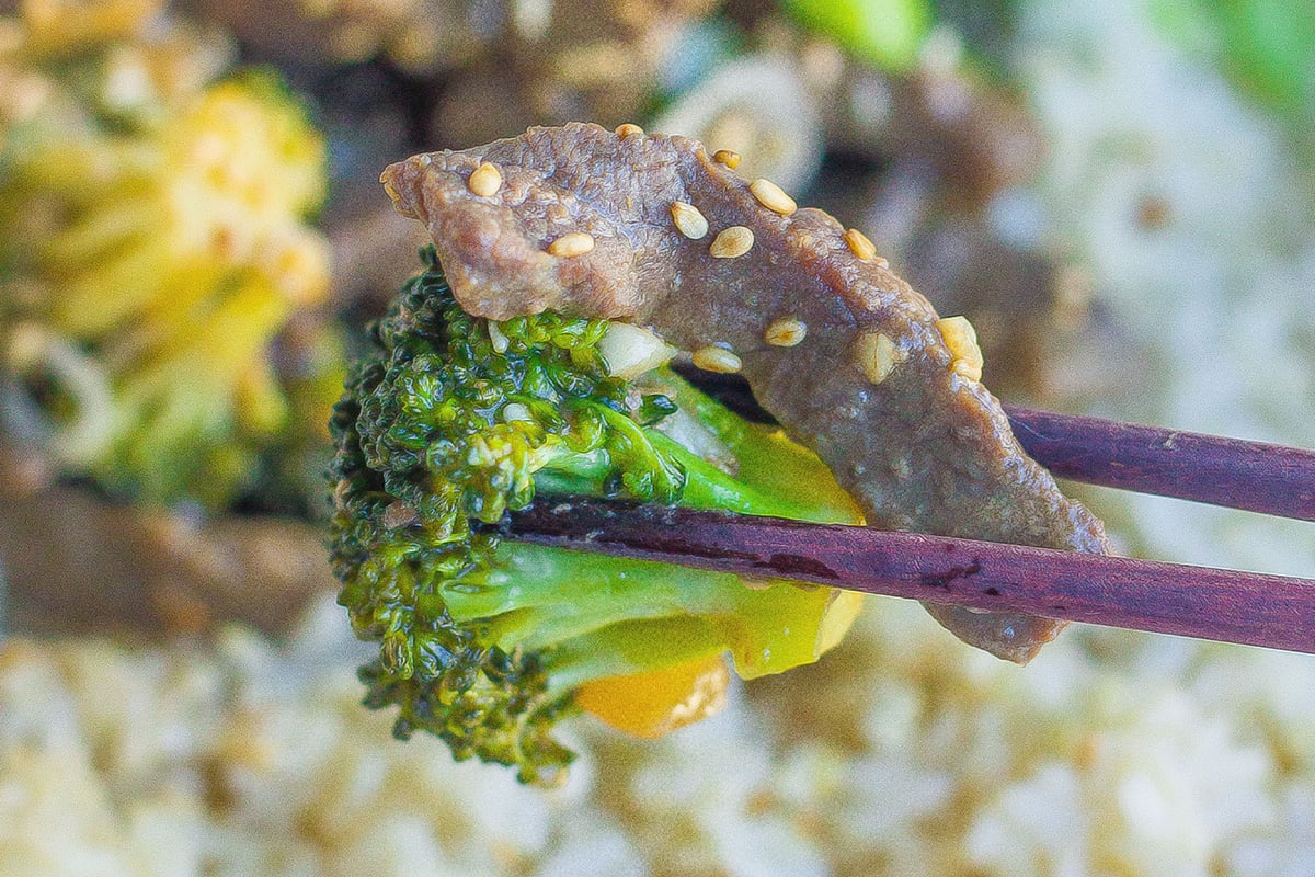 chopsticks holding broccoli and beef 