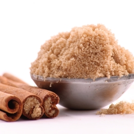 measuring spoon of brown sugar with cinnamon sticks