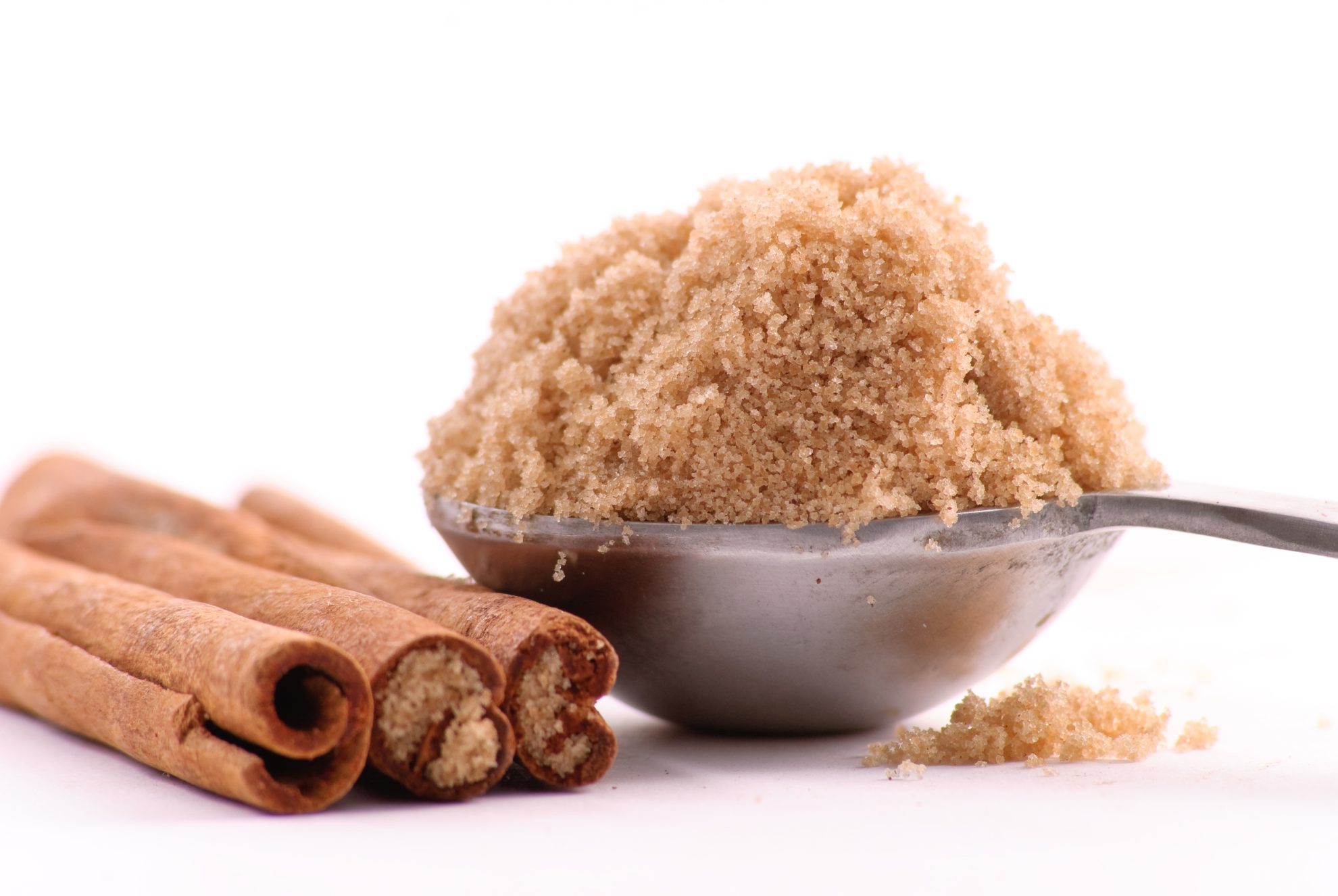 measuring spoon of brown sugar with cinnamon sticks