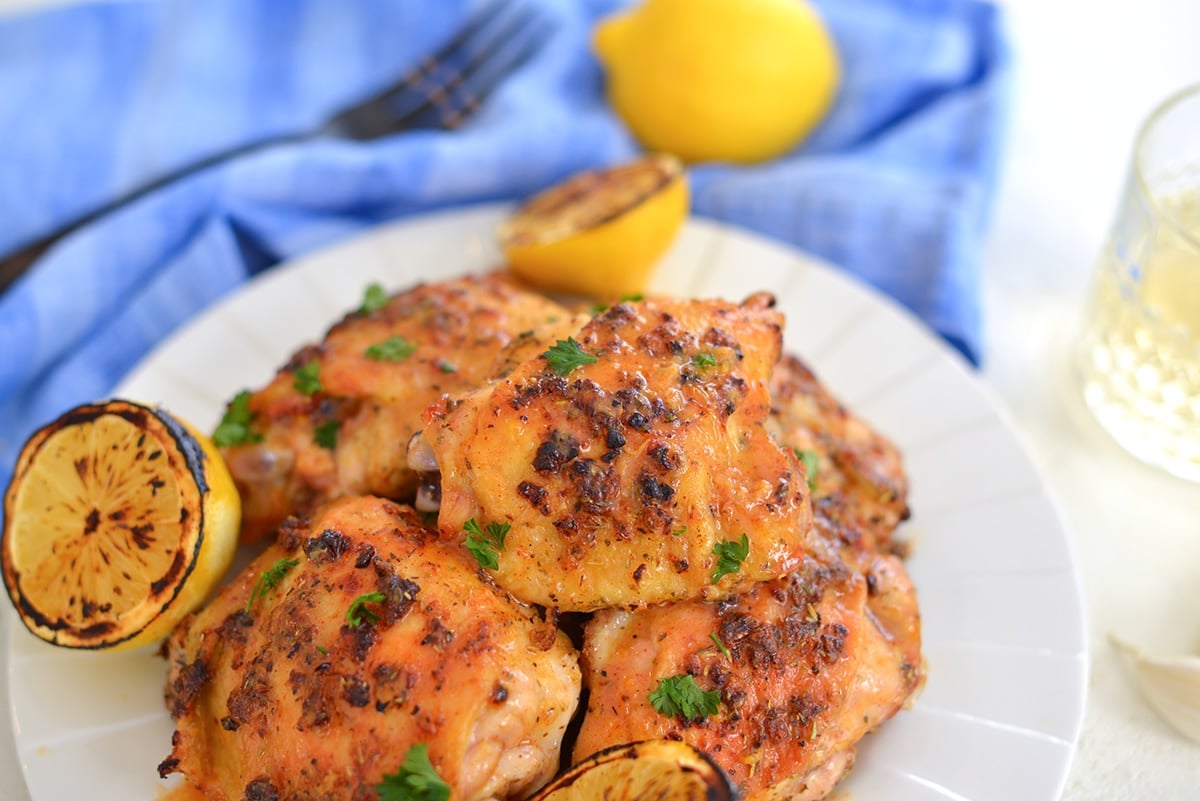 close up of a baked chicken thigh with lemons 