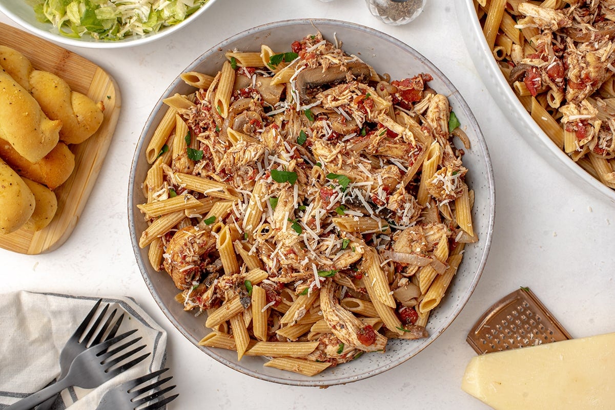 chicken pasta in a large pasta bowl with breadsticks and salad 