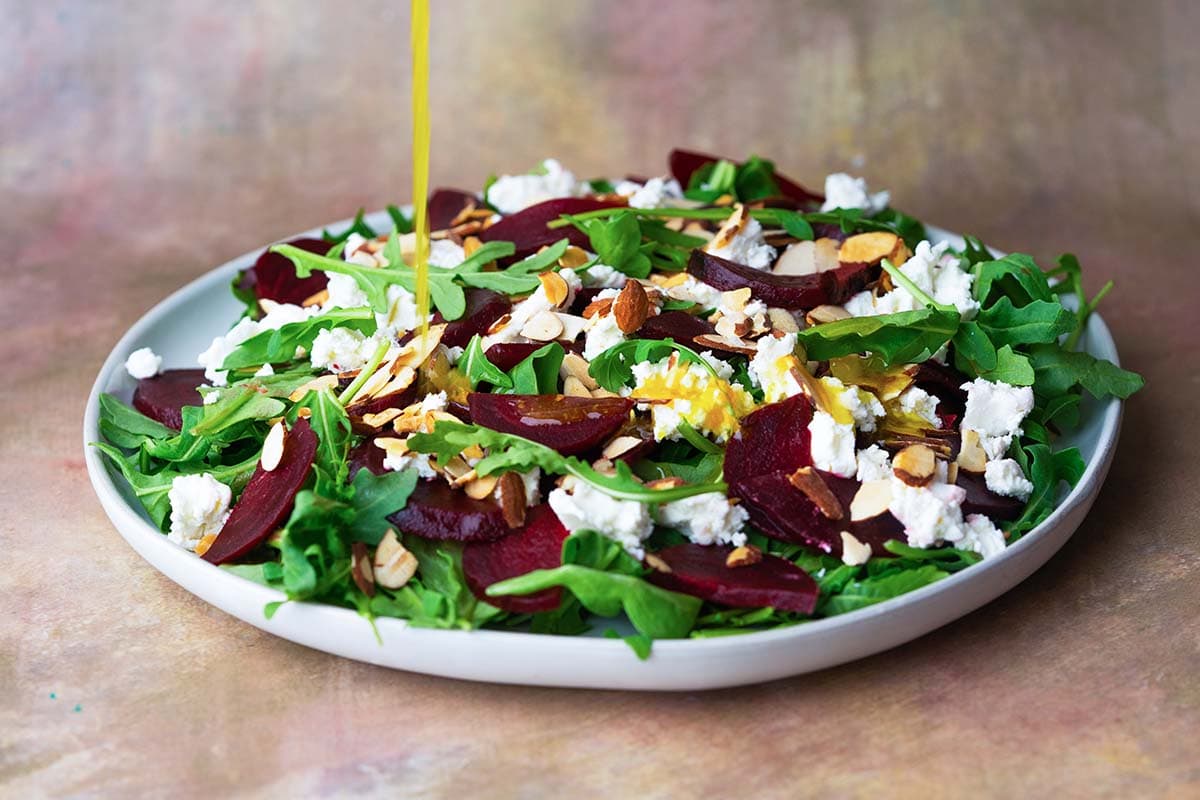 dressing pouring onto a salad on a plate 