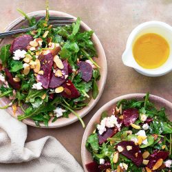 Beet goat cheese salads in two bowls with dressing