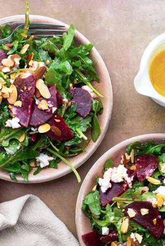 Beet goat cheese salads in two bowls with dressing