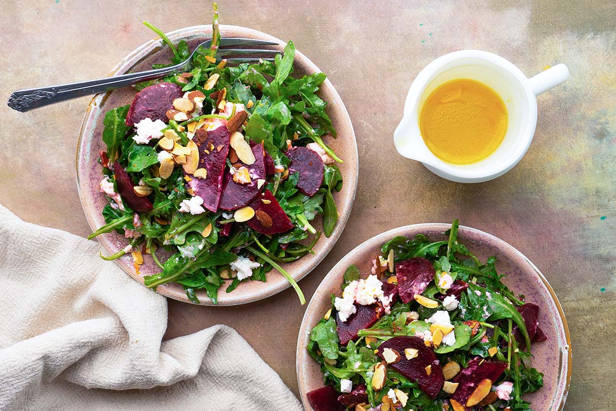 Beet goat cheese salads in two bowls with dressing