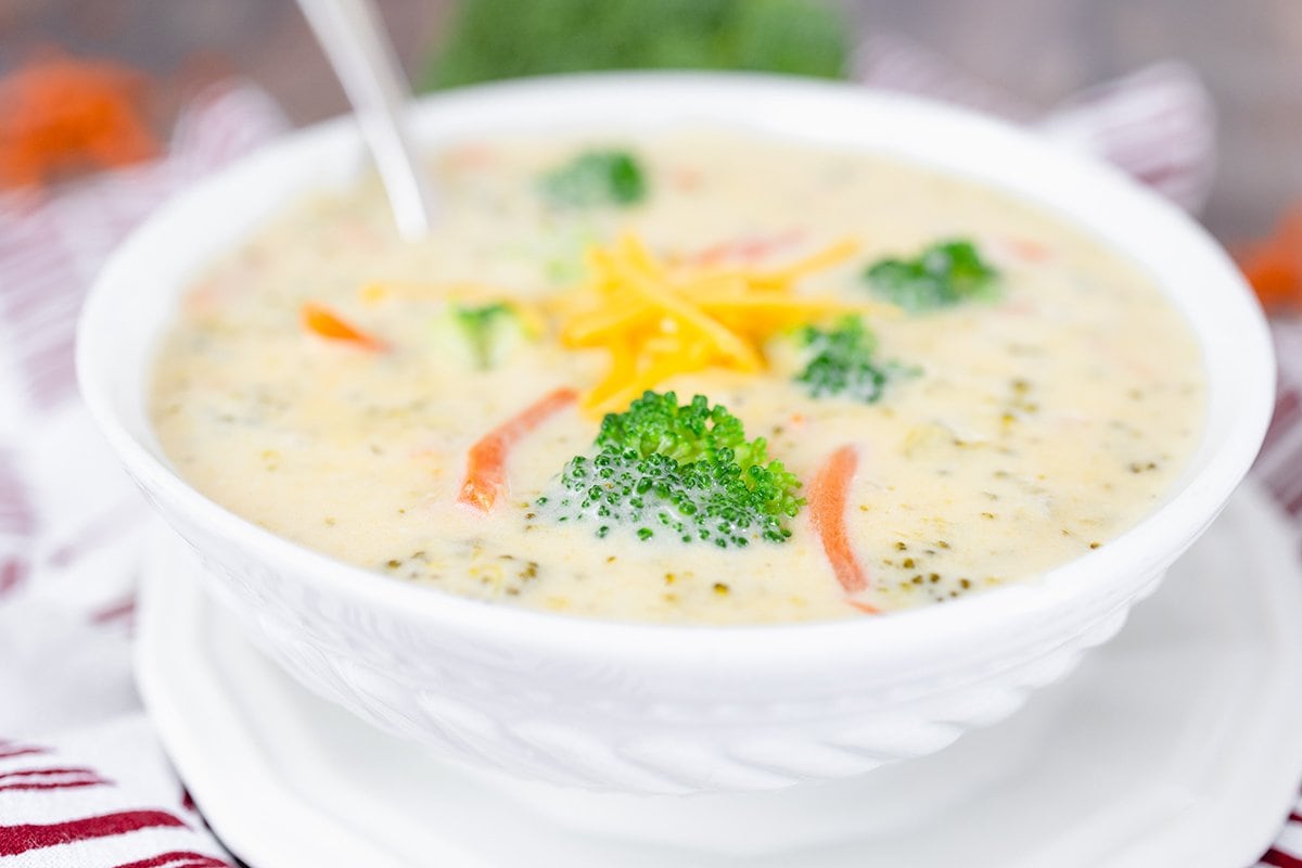 angle view of soup in a white bowl with broccoli and cheddar cheese 