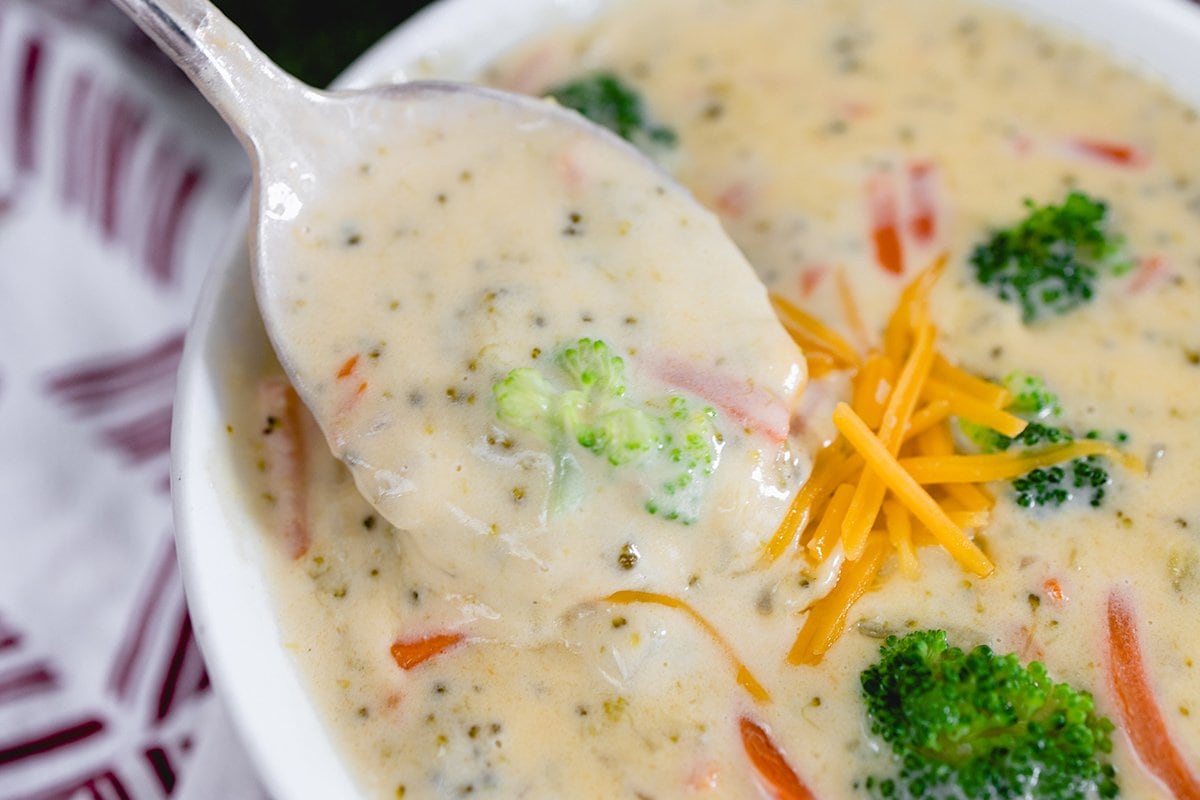 spoon dipping into a bowl of cheese soup 