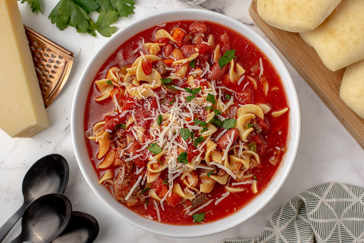 overhead of pasta fagioli soup with cheese and bread 