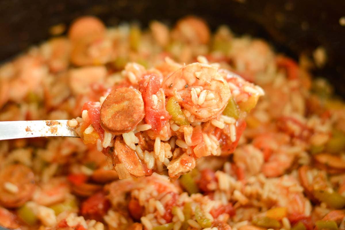 metal spoon holding sausage, shrimp and rice 