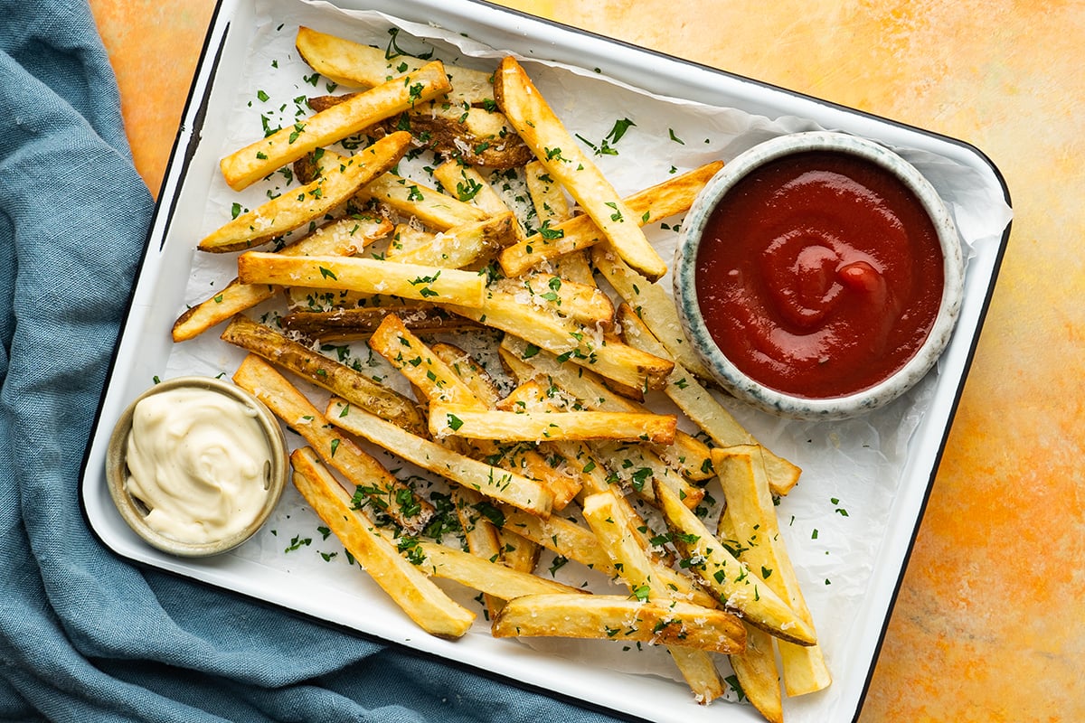 overhead of a tray of french fries with dipping sauces