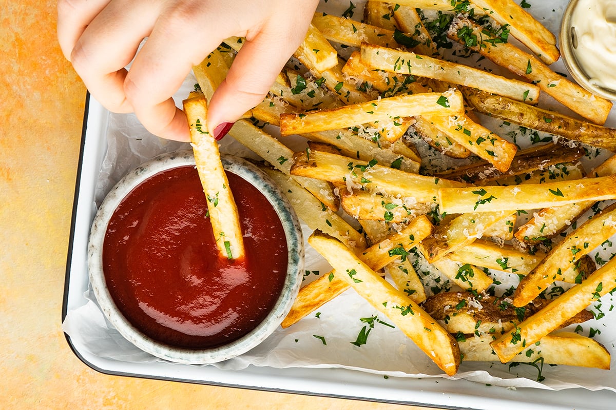 hand dipping a fry in ketchup 